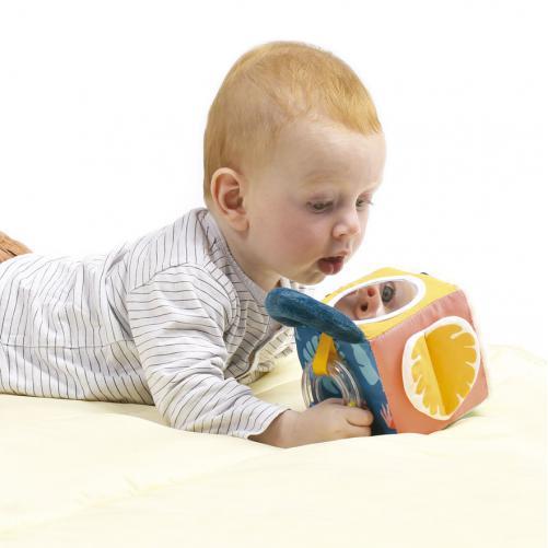 Bebé de barriga para baixo a explorar o cubo sensorial LUDI, com espelho e folha amarela em tecido.