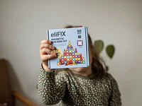 Criança a apresentar a caixa do kit magnético eliFIX Travel de 50 peças.